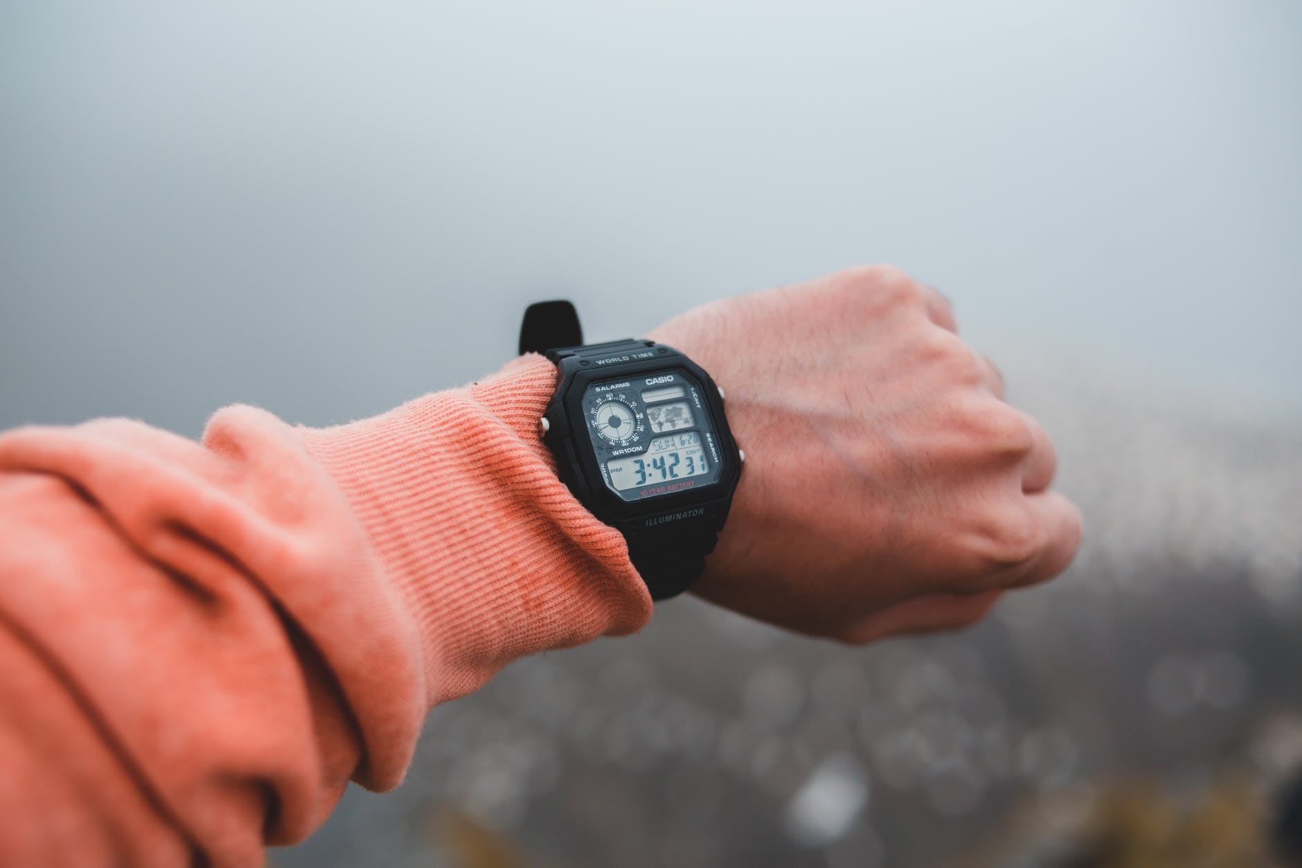 crop man showing modern wristwatch with display on foggy day